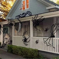 Halloween decorations on a house exterior with large spiders and cobwebs.