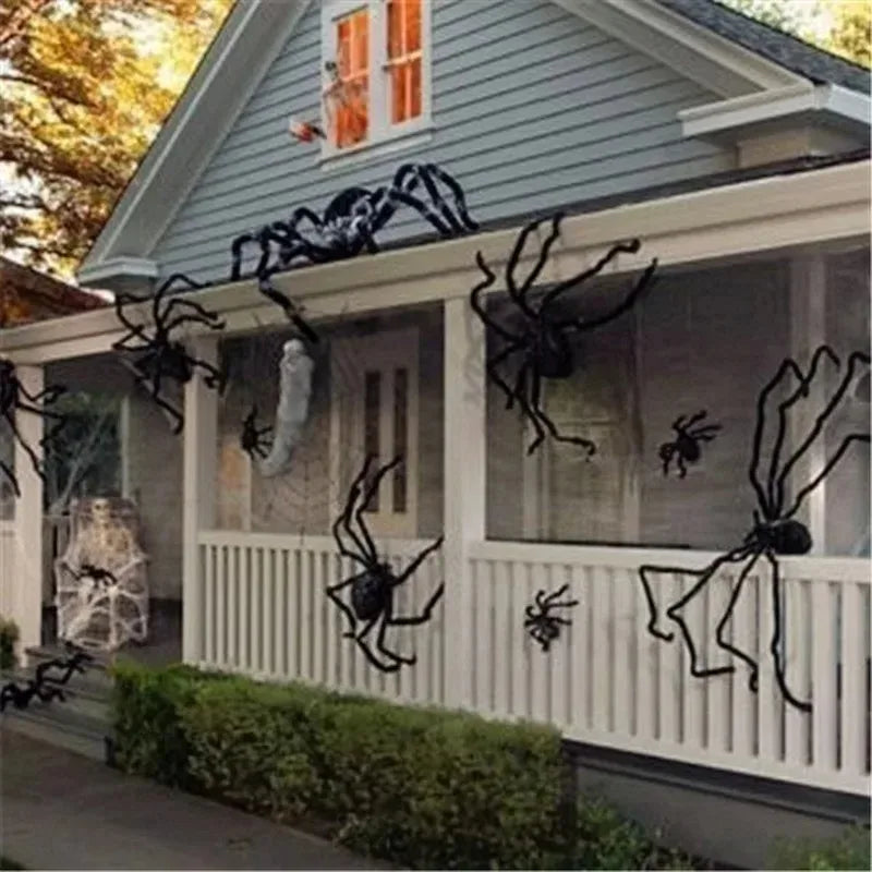 Halloween decorations on a house exterior with large spiders and cobwebs.