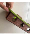 Hand holding a sanding block with green sandpaper on a white surface