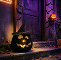 A Halloween-themed scene showing a black woven jack-o'-lantern lantern with a witch hat on stone steps in front of a dark wooden door, with cobwebs, bats, and another glowing jack-o'-lantern in the background.