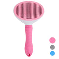 Pink pet grooming brush with a white bristle head on a white background