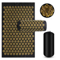 Acupressure mat with black and gold design, rolled up mat, and cylindrical black roller on a white background.