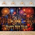 A New Year's Eve themed photography backdrop featuring a Dubai skyline at night with fireworks, water reflections, and 'HAPPY NEW YEAR' text, shown hanging in a room mockup with pendant lights and a wooden floor.