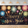 A New Year party backdrop banner featuring colorful fireworks in gold, blue, green, red, and purple over a dark background with 'Happy New Year' written in gold glitter script. The banner is shown hanging in a mockup with four hanging lamps above and a wooden floor below.