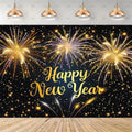 A New Year's Eve party backdrop featuring a black background filled with golden and purple fireworks, with 'Happy New Year' written in elegant gold script. The backdrop is shown hanging in a room mockup with four hanging pendant lights above and a wooden floor below.