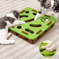 Two cats playing with a green and brown cat puzzle toy on a carpeted floor.