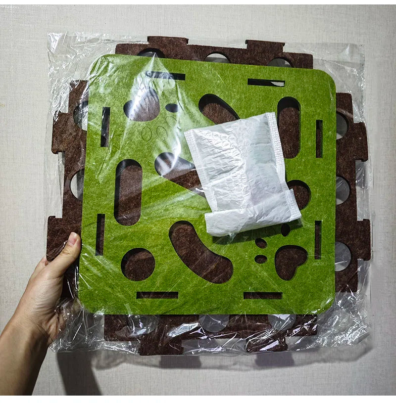 Green and brown interlocking foam puzzle mat with a white cloth inside, held by a hand against a light gray background.
